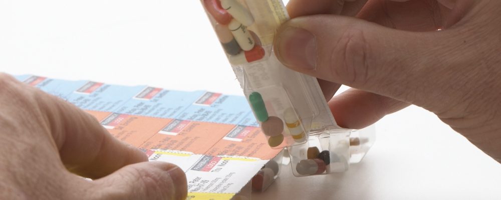 Hands filling a multi-dose blister pack card